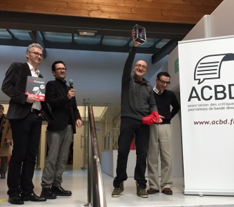 de gauche à droite : Fabrice Piault, président de l'ACBD, Antoine Guillot, vice-président, Antonio Altarriba brandissant le trophée et Keko, dessinateur de Moi, Assassin